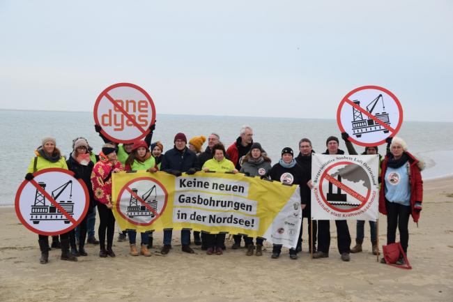 Menschen protestieren am Strand und halten Banner und Plakate gegen die Gas-Bohrungen im Wattenmeer hoch. 